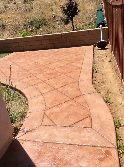 Terracotta-coloured stamped concrete walkway with a pressed border pattern along each edge