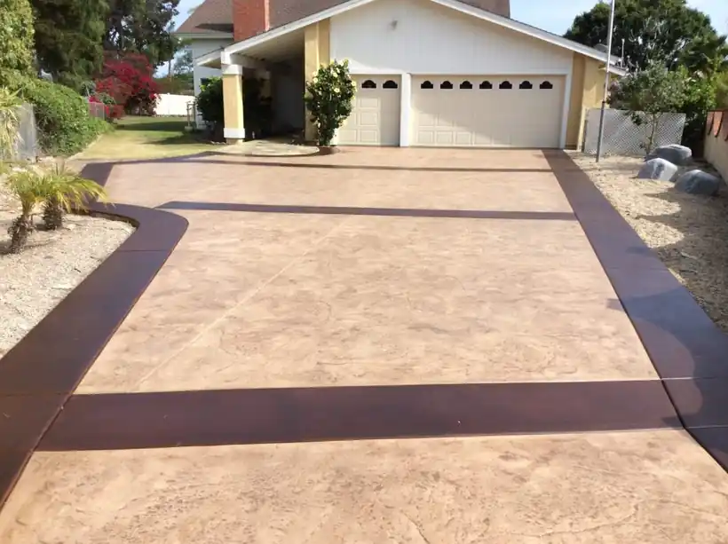 Stamped concrete driveway with a dark stained border band leading to a two-car garage