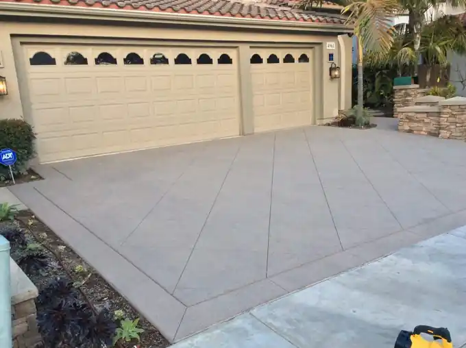 Broom-finish concrete driveway running up to a three-car garage