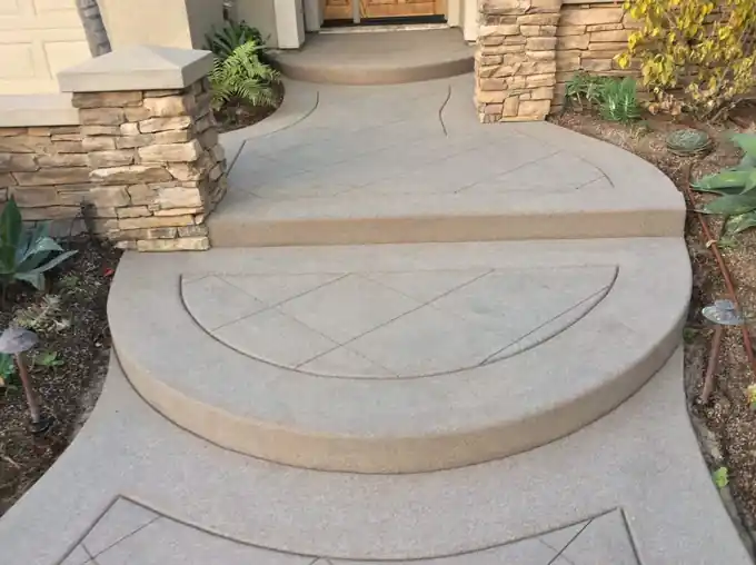 Curved concrete entry steps with scored circles between stacked-stone columns
