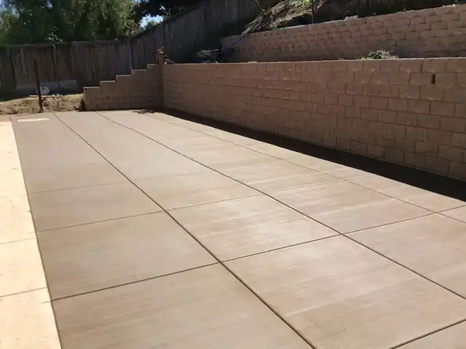Broad scored concrete slab running up to a block wall