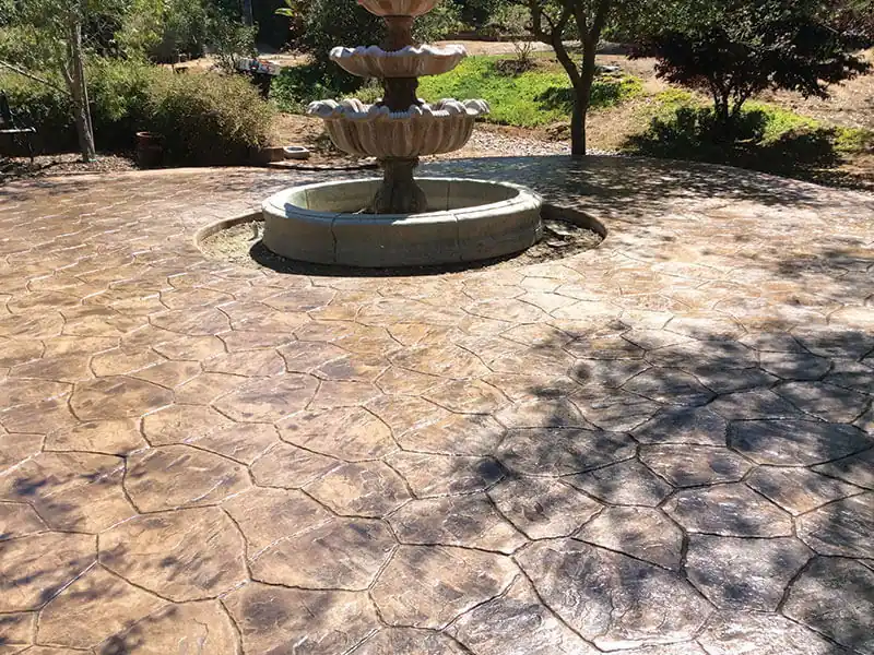 Stamped stone-texture concrete patio around a garden fountain
