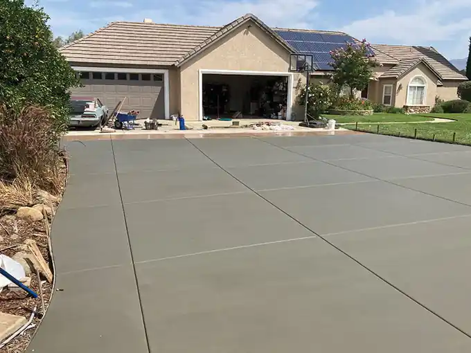 New broom-finish concrete driveway beside a stone-columned entry