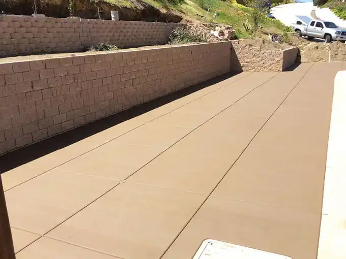 Wide finished concrete slab running up to a block retaining wall