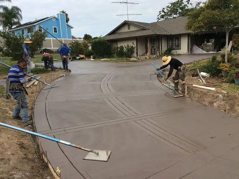 Albert Cruz Jr Concrete crew trowelling a freshly poured curved driveway in front of a house